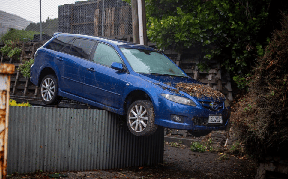 Image of blue mazda on top of fence after floods