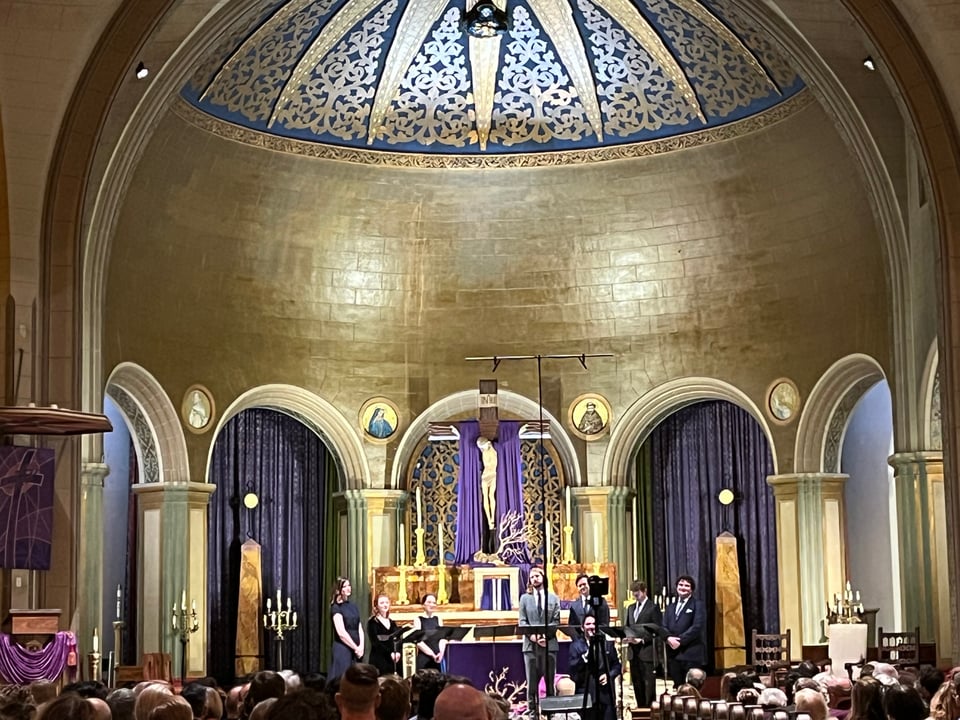 a group of eight singers stands in the front of a church under a beautifully mosaiced dome