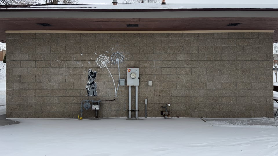 Concrete brick wall with a stencil of white dandelions and a gray and black girl holding dandelions