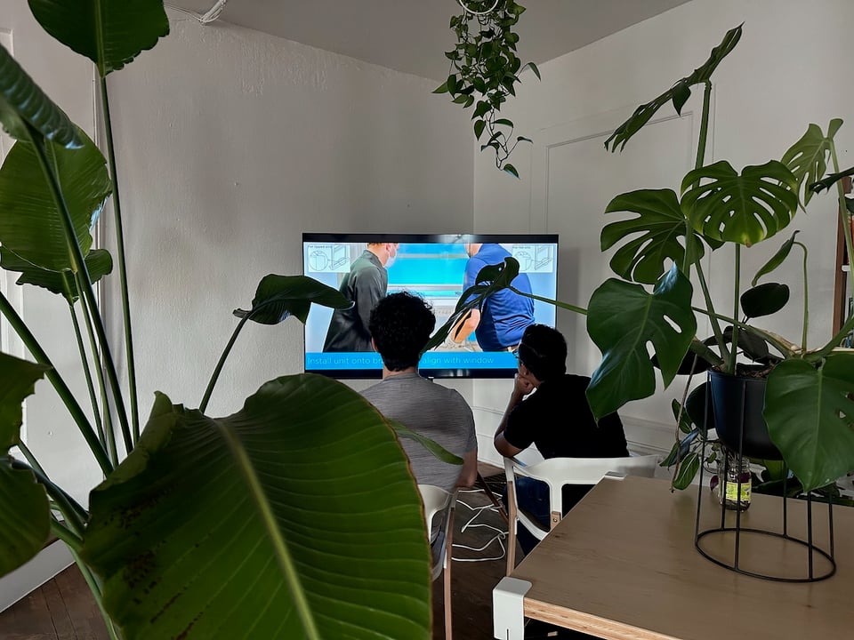 Ivan and Norton looking at a TV, watching a tutorial