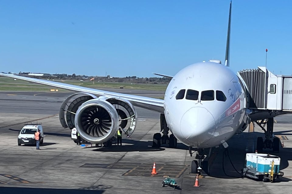 An airplane is shown and the turbine engine is open with people trying to repair it.