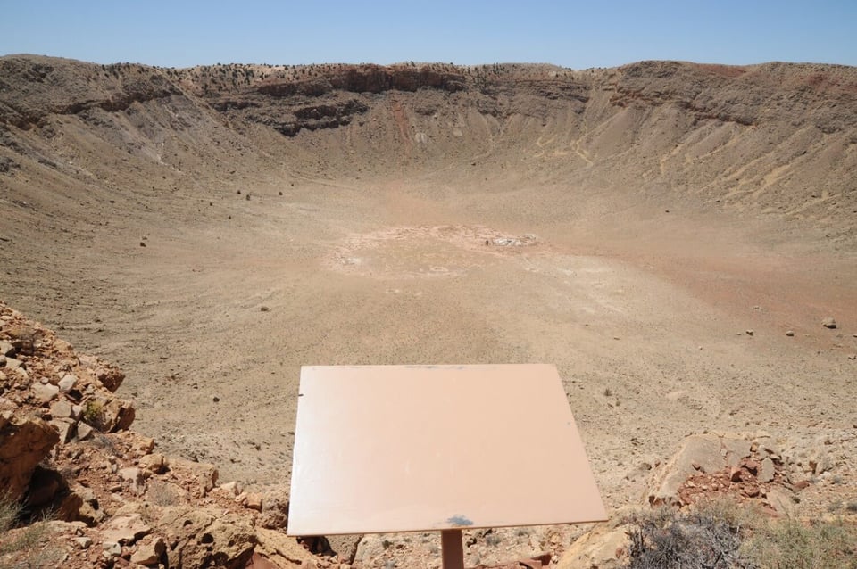 A blank plaque on the rim of a large desert crater