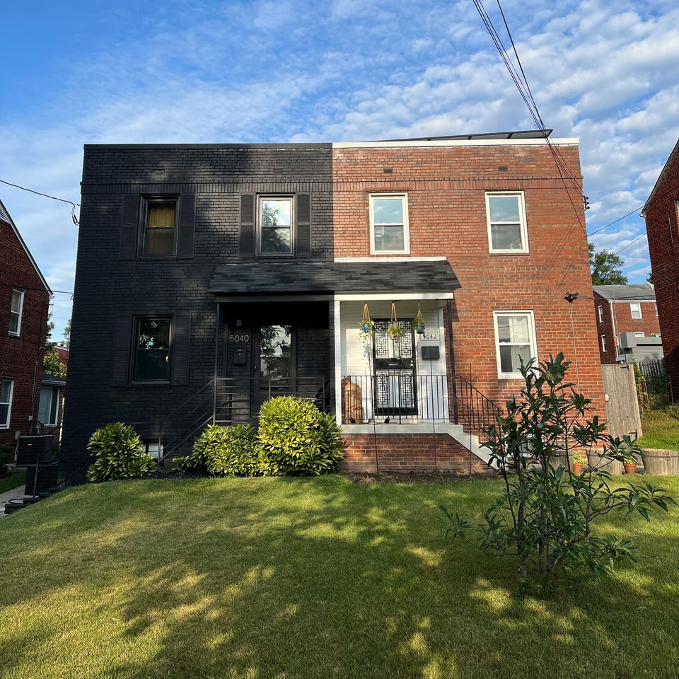 A pair of rowhouses: one black, one red brick.