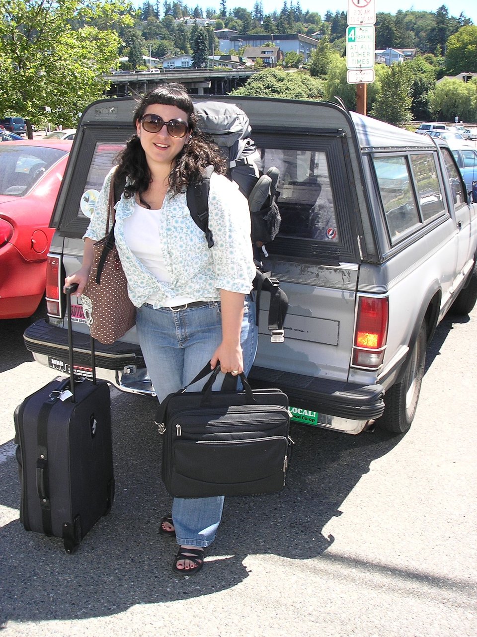 Wendy is standing in front of a truck with a cab, laden with a backpack, suitcase, and computer bag, 2007.