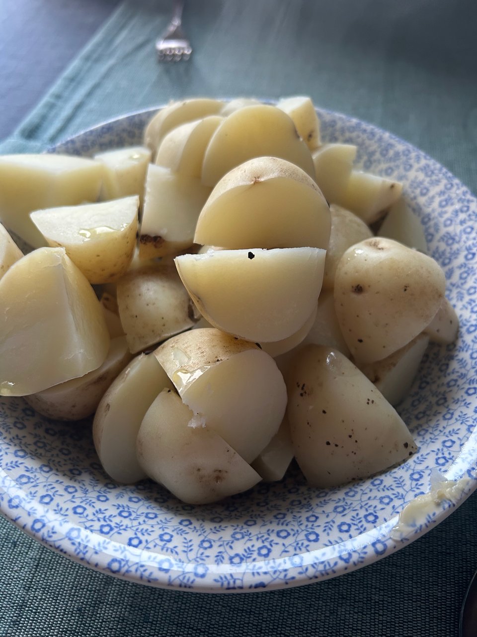 A blue and white bowl of boiled new potatoes.