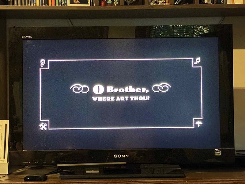 A photo of my television, which in this instant displays the title of the movie O Brother, Where Art Thou? in an old timey font.