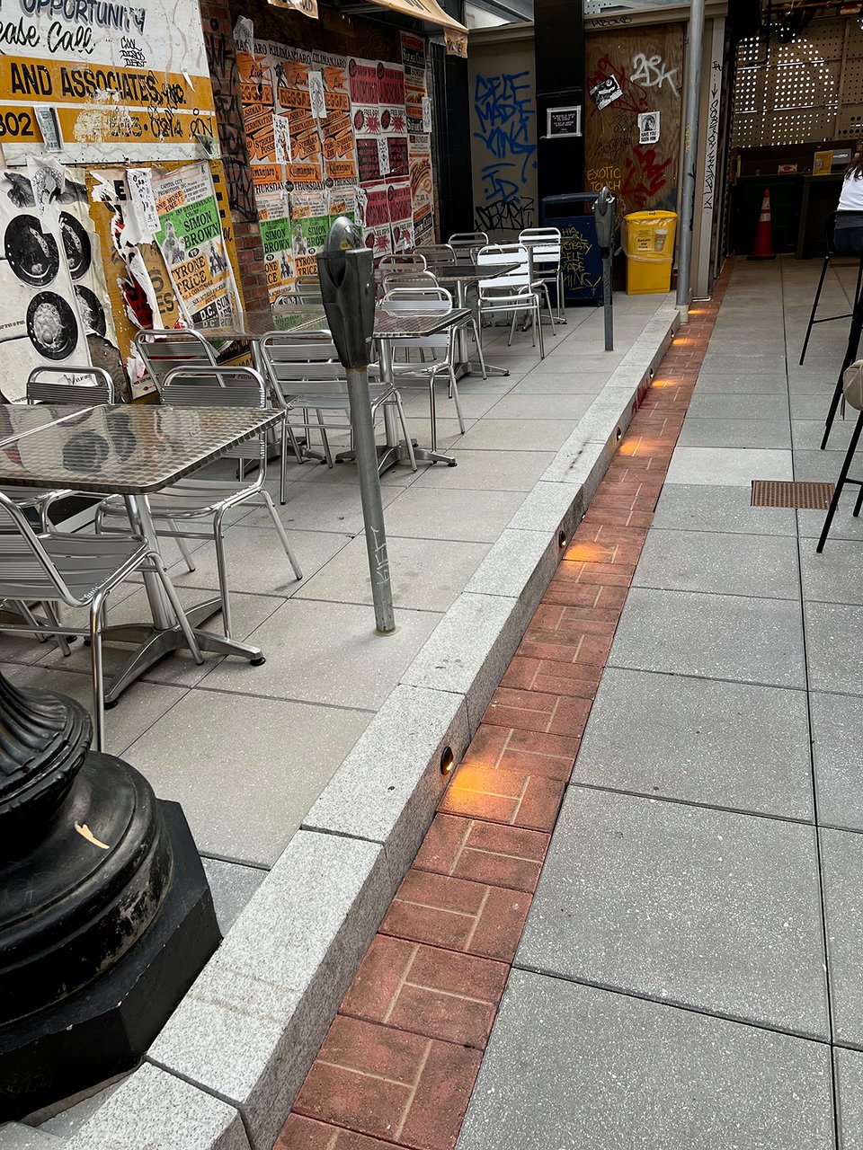 a sidewalk with tables and chairs