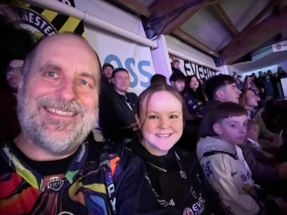 Selfie of a man and a teenaged girl in the crowd in an arena.