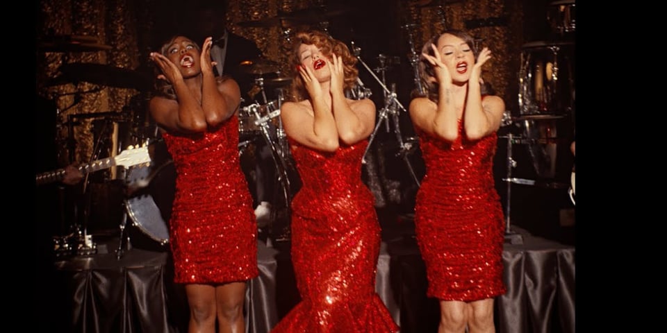 The music video for Where is my husband? - three singers in red sparkly dresses.