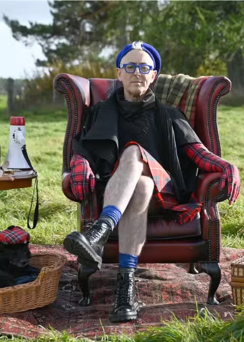 Alan Cumming sitting in a chair outside