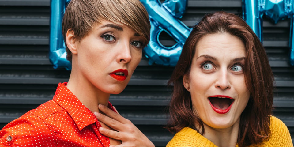 Two improvisers with balloons behind them.