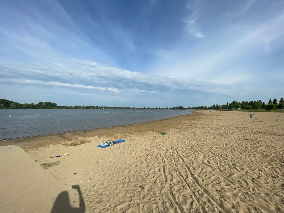 A lakeside beach with blue sky and clouds.
