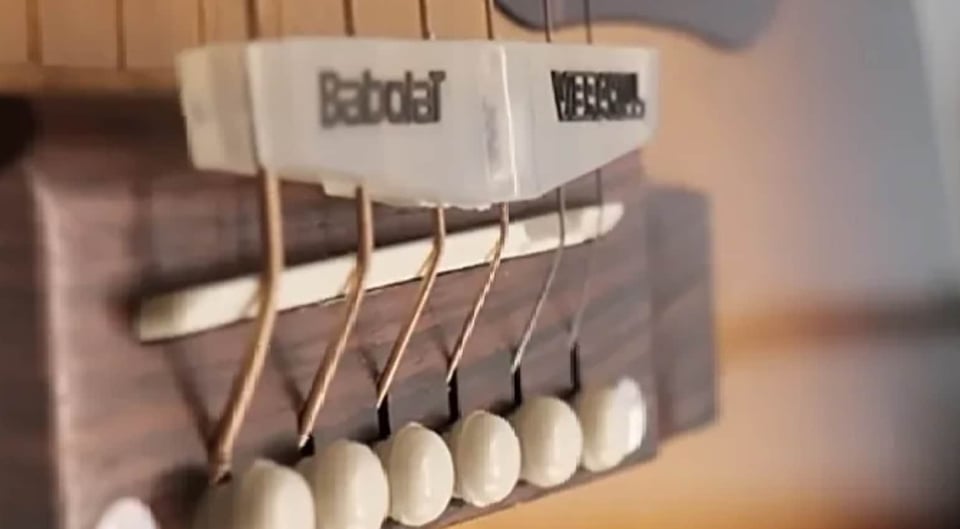 a tennis racket vibration dampener fit between guitar strings at the bridge