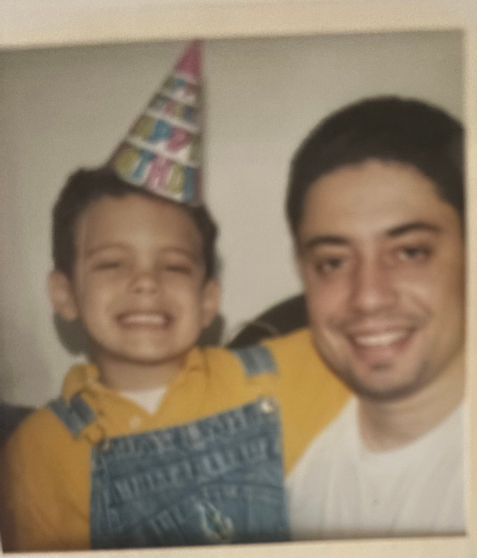 me as a kid in a party hat, and my godfather Francisco next to me. We're both cheesin'.