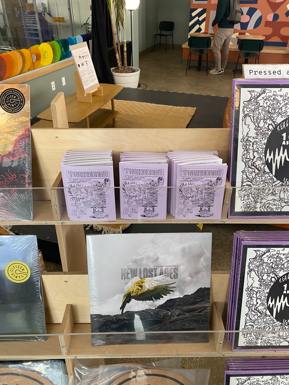 A stack of Train Songz zines on a shelf with vinyl records
