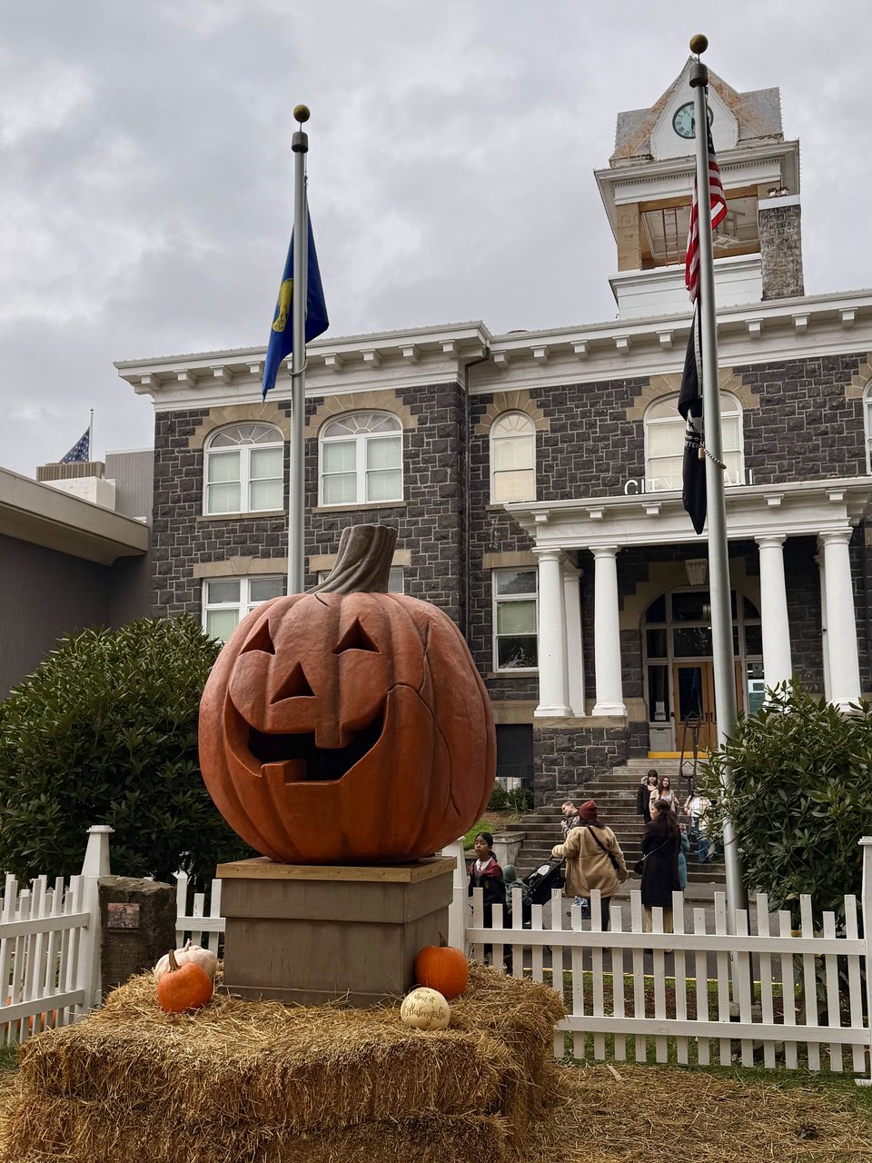 A large pumpkin on a pedestal sits in front of a town hall
