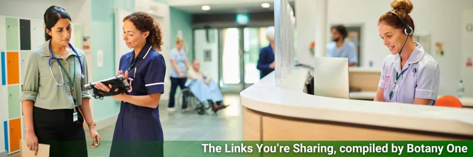 A nurse speaks to a doctor in a hospital, elsewhere a nurse is managing reception