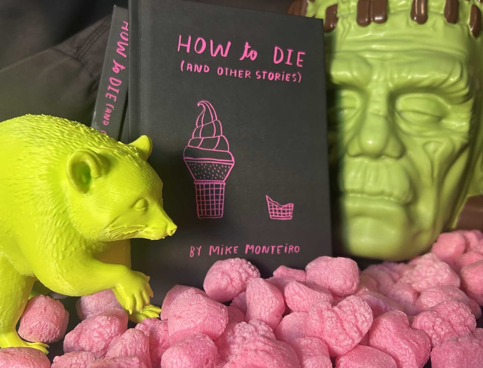 A ridiculous diorama including my book, How to die, a 3-d printed acid green Jimothy, and a green chocolate Frankenstein from Costco. All sitting on a bed of pink packing hearts.