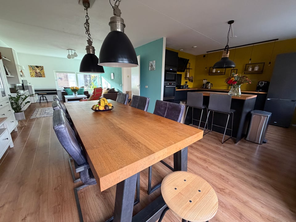 A dining room / living room is shown with the kitchen in the background. Everything is clean and staged ready for a showing.