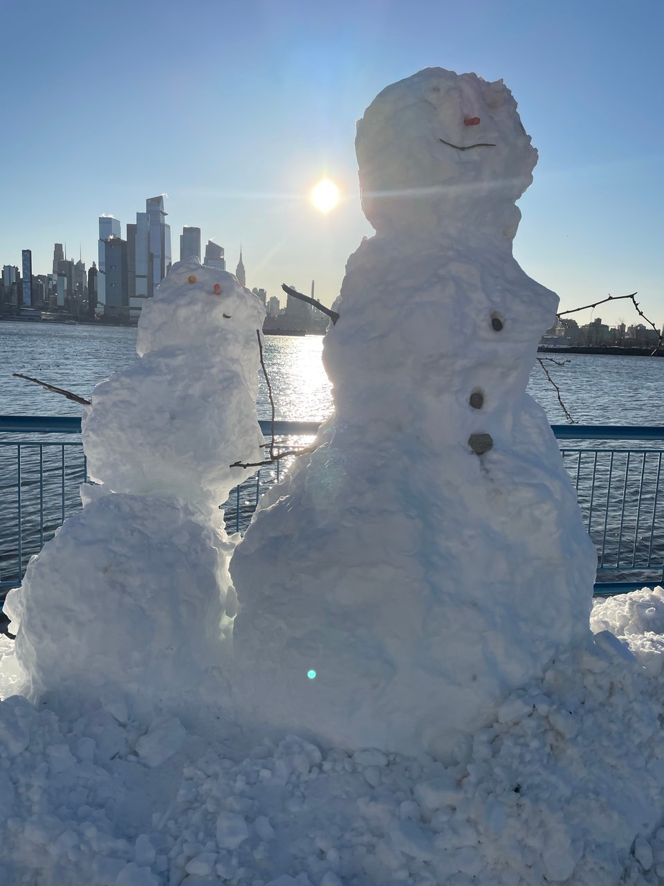 A pair of snowmen with NYC in the background