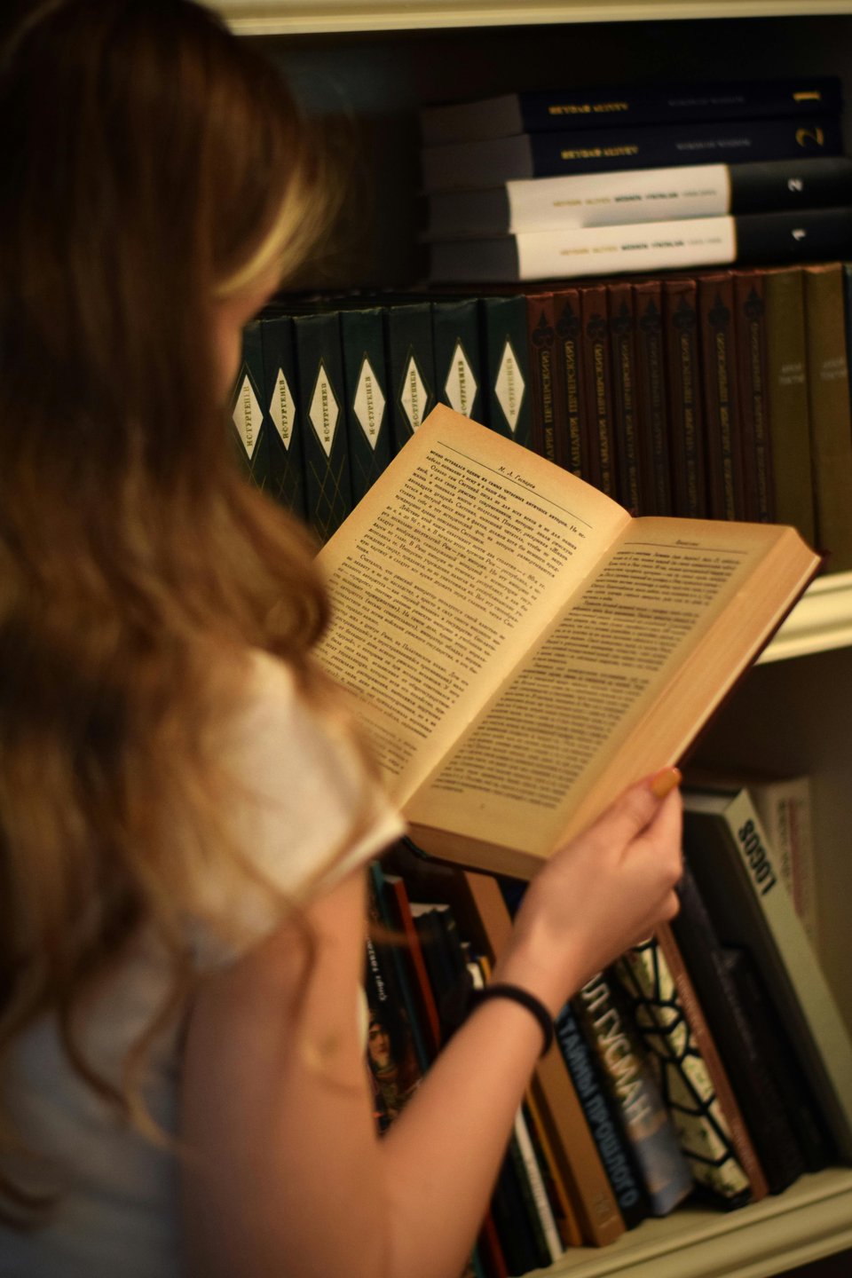 Stock image of a person (face not shown) reading an open book.