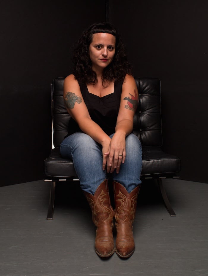 a woman in cowboy boots sitting on a black chair