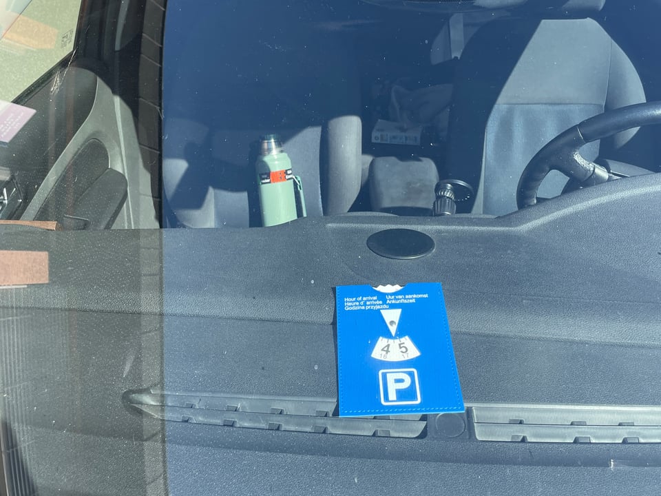 Dashboard of a car with a blue panel on it telling the time when the car was parked.