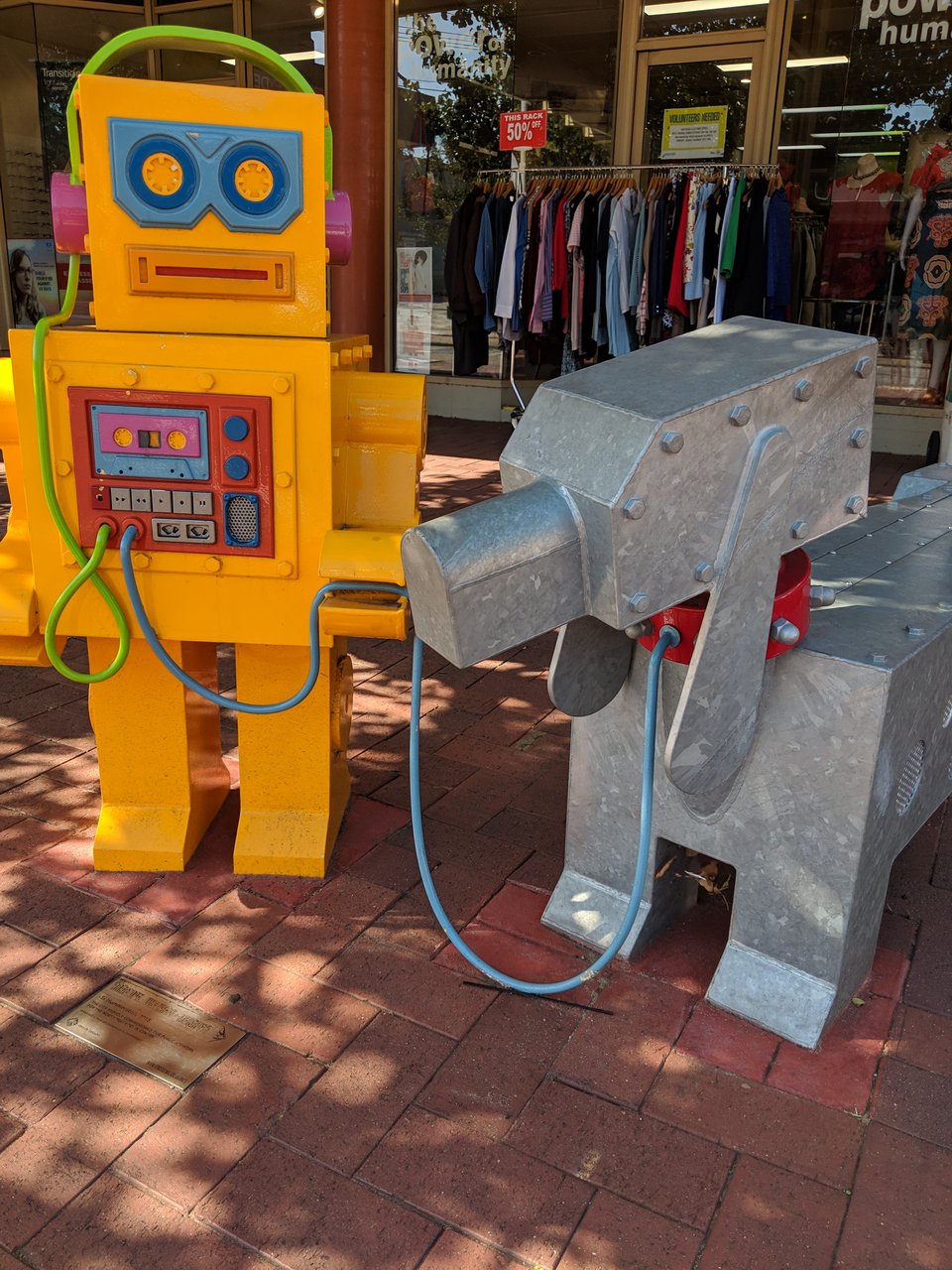 A tape deck robot holding the leash of a robot dog