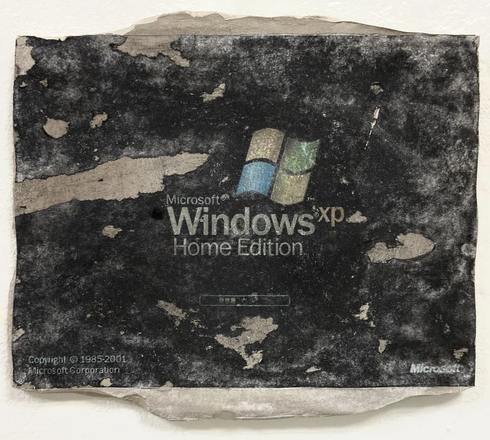 Artwork that depicts the boot screen for Microsoft Windows XP home edition. The logo and name of the software is in the center of the screen, and the screen itself is black. Beneath the logo is a small progress bar showing how the software is loading, and in the bottom corners are the copyright information and the logo for Microsoft. The painting is incredibly corroded and messed up, because it appears to have been painted on what looks to be stone or parchment, with many parts of the screen worn off, exposing the stone or parchment below. It looks like something that was buried in the earth for 100 years and then pulled out again