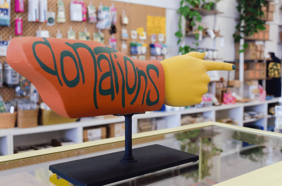 A sculpted hand pointing to the back of the store with "Donations" painted on it