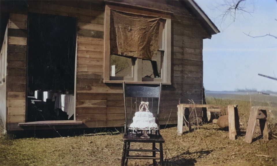 a cake sits on a chair in front of a clapboard house