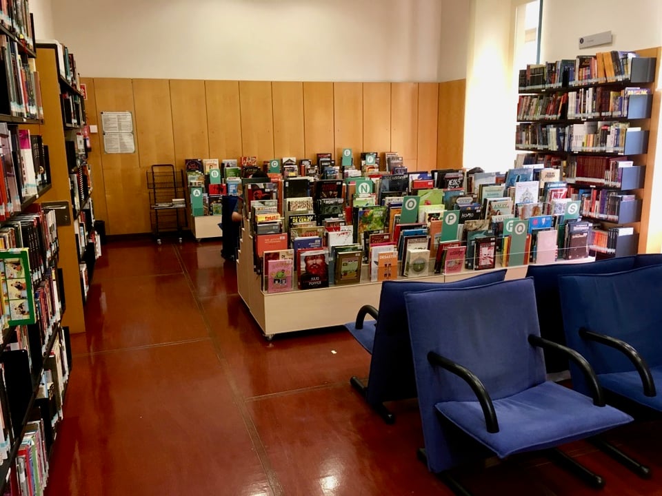 The other side of the comics reading room. The walls contain large part of the collection while in the middle a series of bins contain a sizeable collection of newer comics. There are also some sits where people can sit and take time to read the comics.