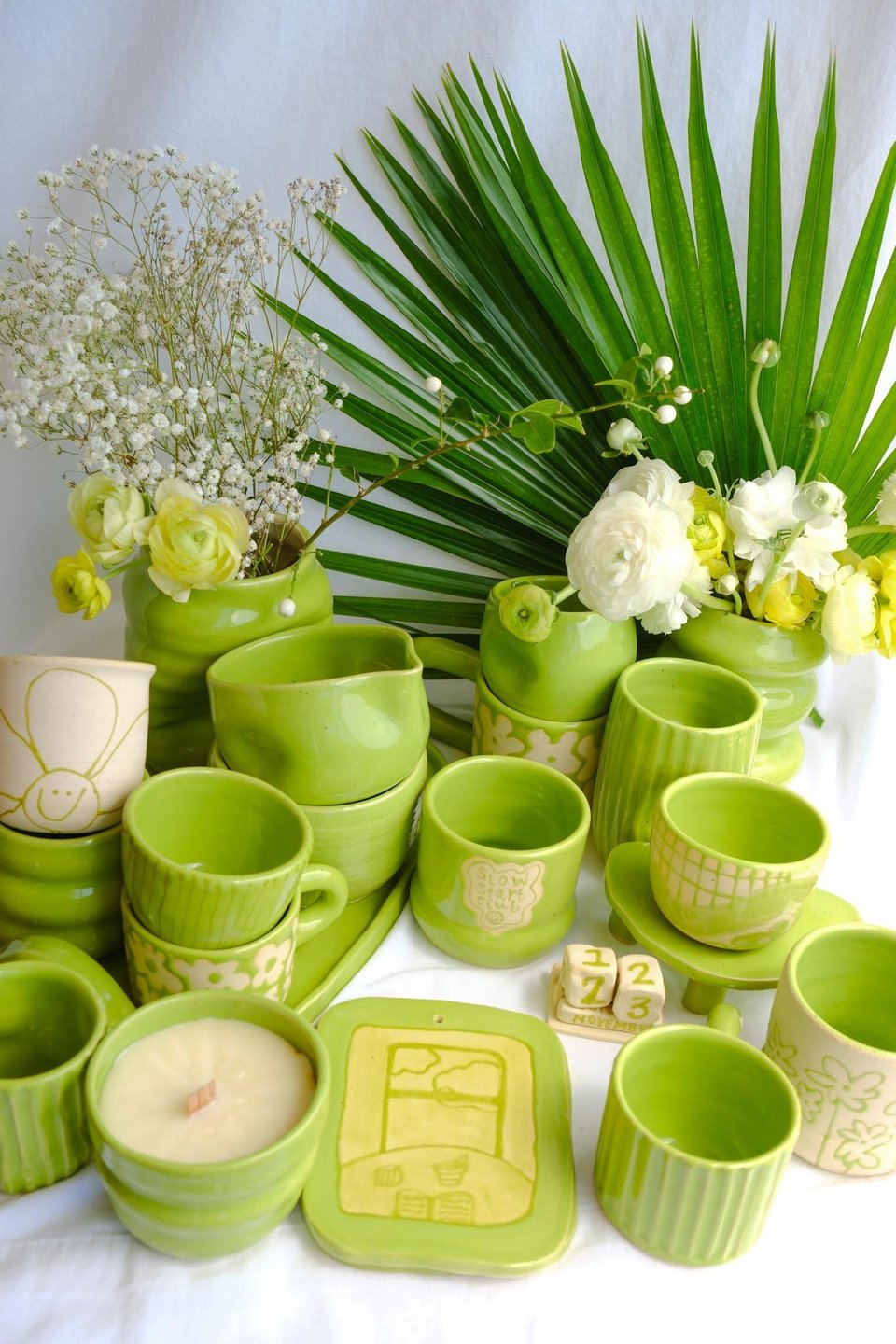 An image of green ceramics surrounded by plants.