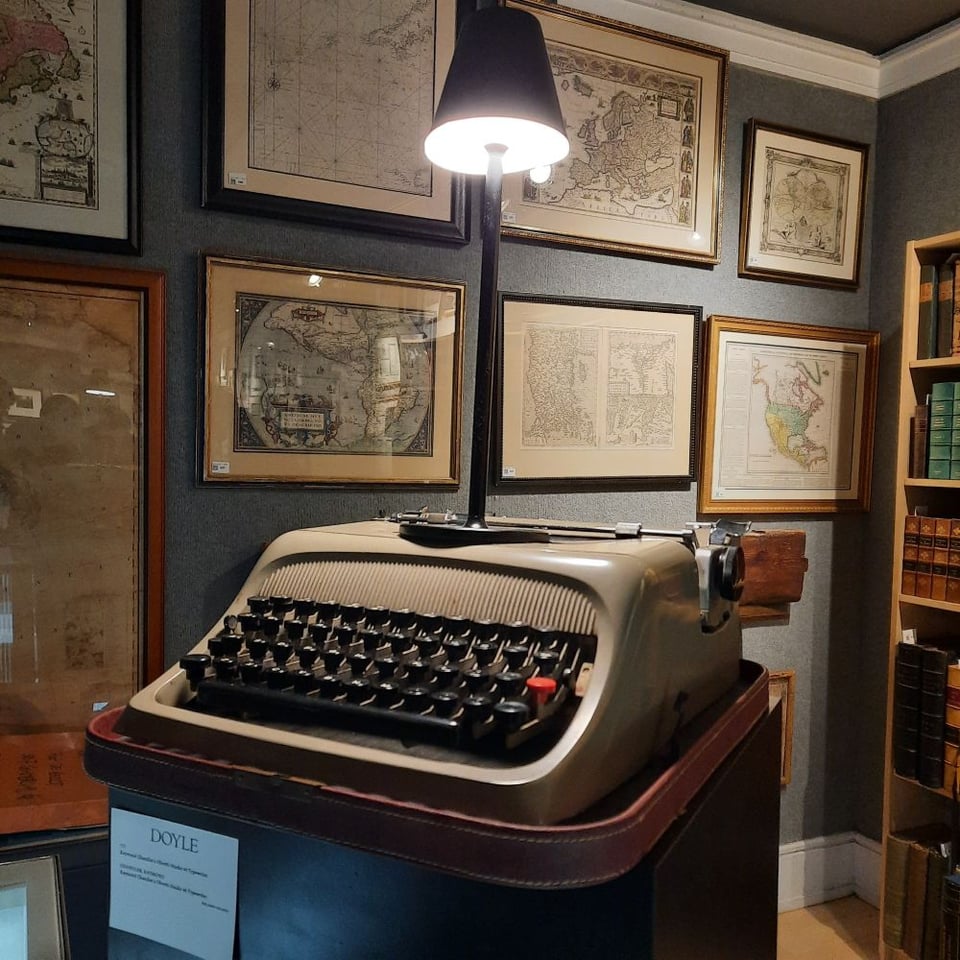 a manual typewriter situated near framed photos of maps and other images