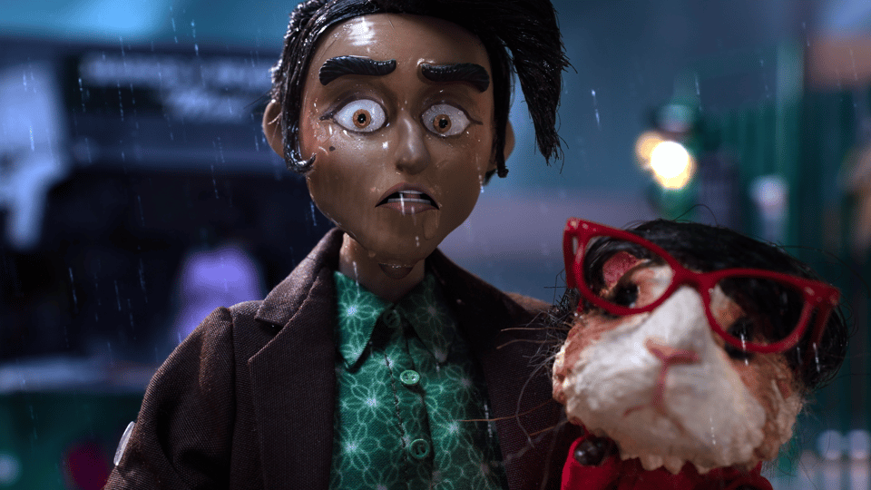 A woman stands in the rain looking shocked, while holding a guinea pig which wears bright red glasses