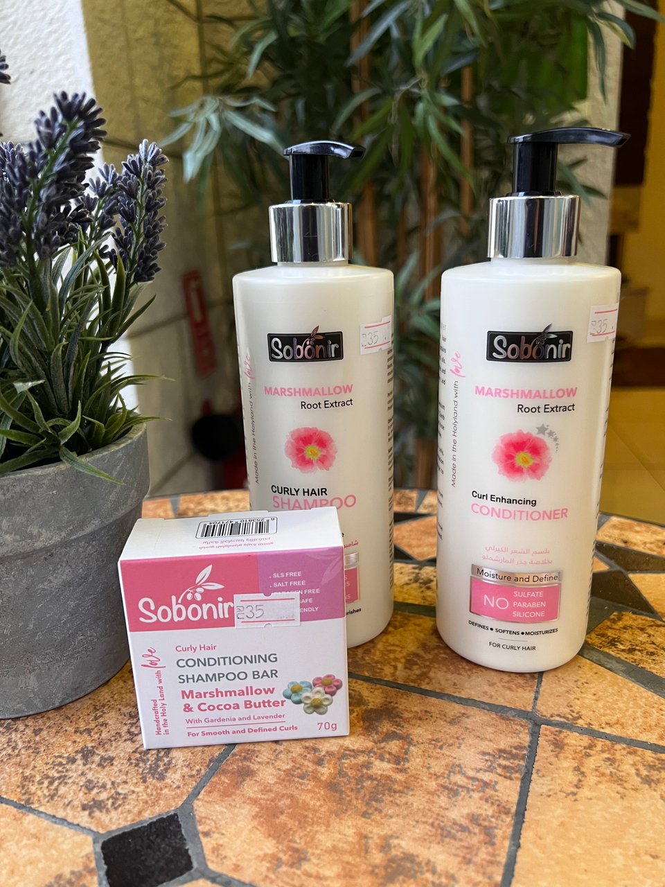 Two bottles, shampoo and conditioner. Both are white with pink flowers. And a box that is labeled 'conditioning shampoo bar'