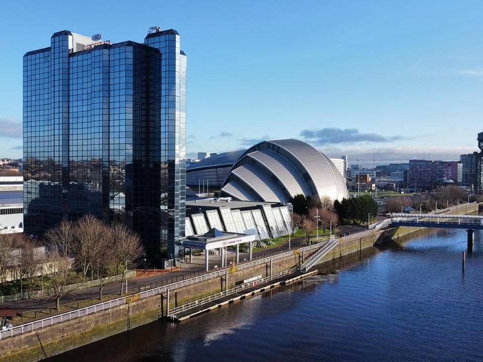 Photograph of a tall glass-clad building next to a river