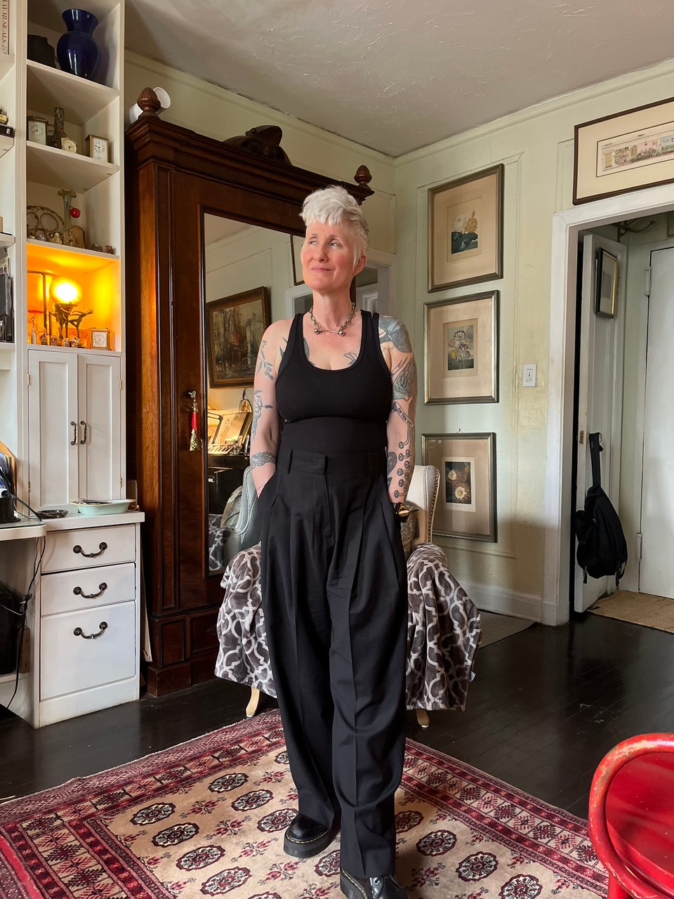 Me now, smirking in loose fitting black trousers, a black tank top and platform docs. My hair is short, masculine, and silver.