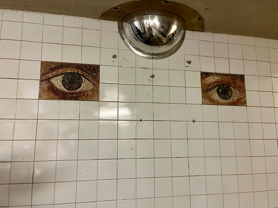 white subway tiles with two tiles that are eyes, with a security half-globe on top