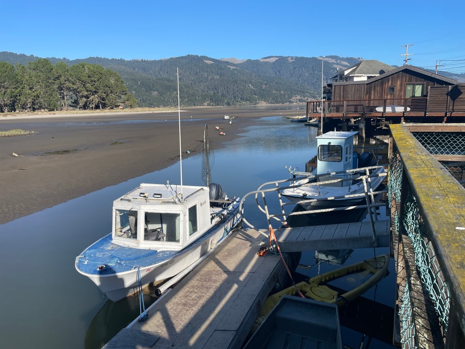 A boat docked next to a pier in a low tide lagoon.
