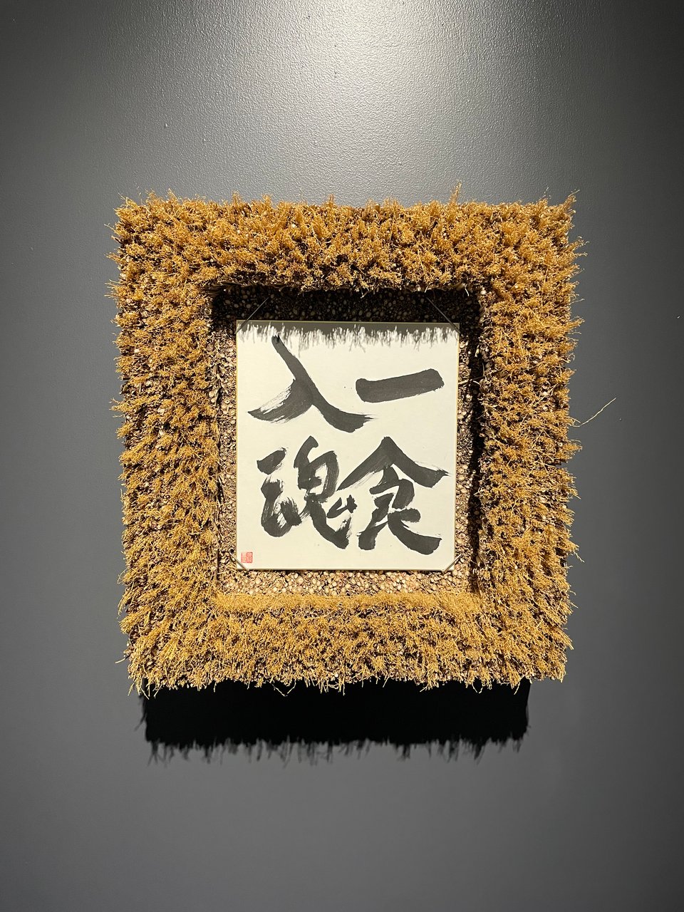 A framed calligraphy piece reading 一食入魂.