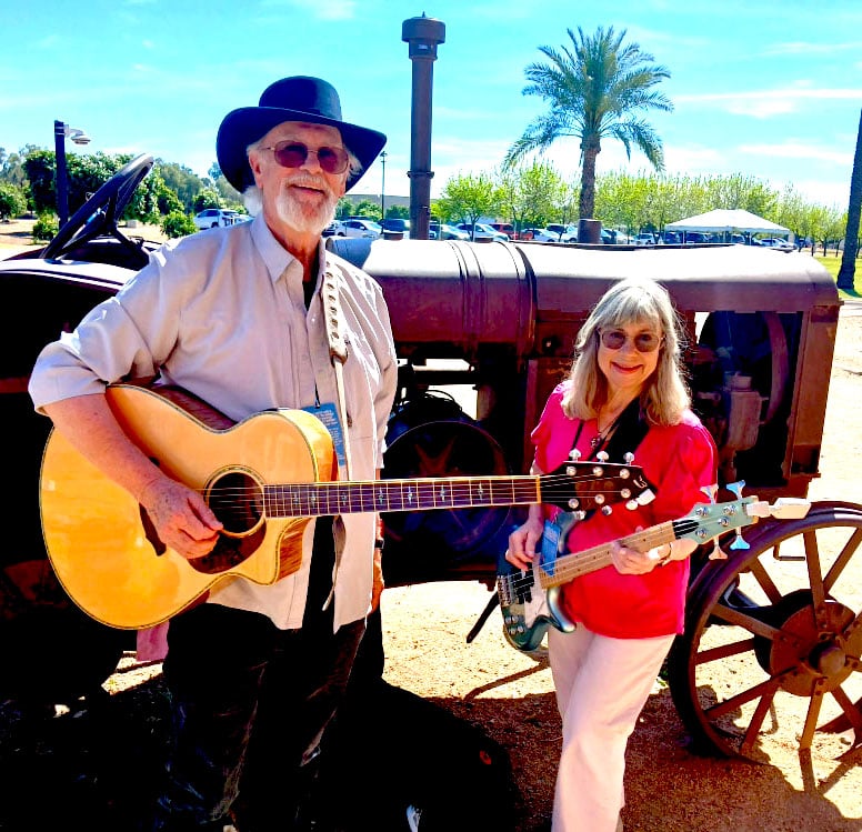 A Picture of Steve and Kristi Nebel with guitars in front of a tractor