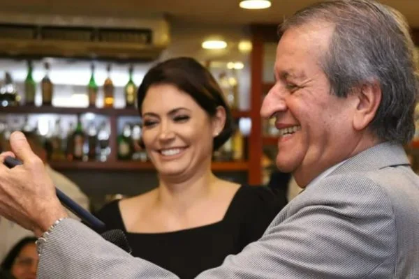 Foto de Michele Bolsonaro sorrindo ao lado de Valdemar Costa Neto, que também sorri
