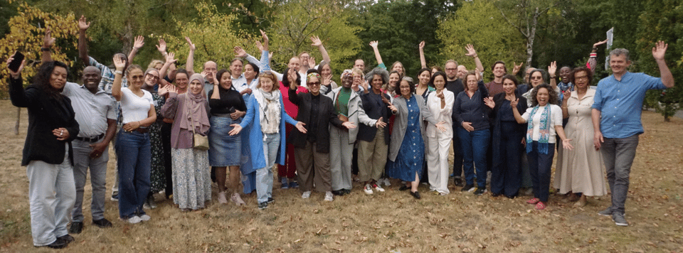 A group picture of the Sandpit participants standing in a foresty area and raising their hands in enthusiasm.