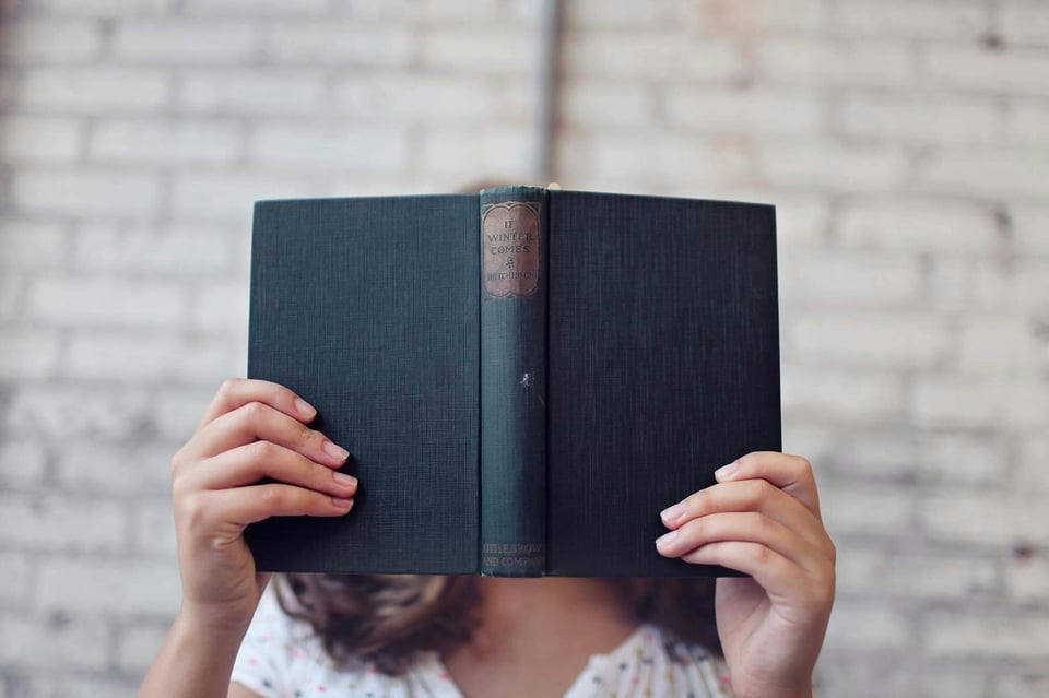 Image of a person (face not shown) reading an open blue book.