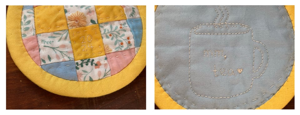 Two photos side by side. First photo: A round, colorful patchwork lid with yellow binding around the edge and hand quilting inside each square. The patchwork is made of one inch squares with yellow, pink, and blue solids mixed with squares made with a white background and floral designs on them. The year 2024 is embroidered onto one of the squares. Second photo: The underside of the lid shows a light blue solid background with a steaming tea mug embroidered onto it. The words "Mm, tea" are stitched on the mug with a little heart. The yellow binding looks even more lovely on this side from the hand stitching.