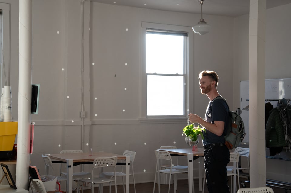 A man holding a disco planter in a bright room.