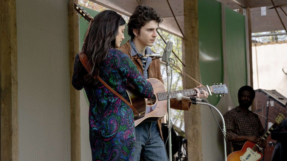 A scene from A Complete Unknown with Bob Dylan (Timothee Chalamet) and Joan Baez (Monica Barbaro) singing.