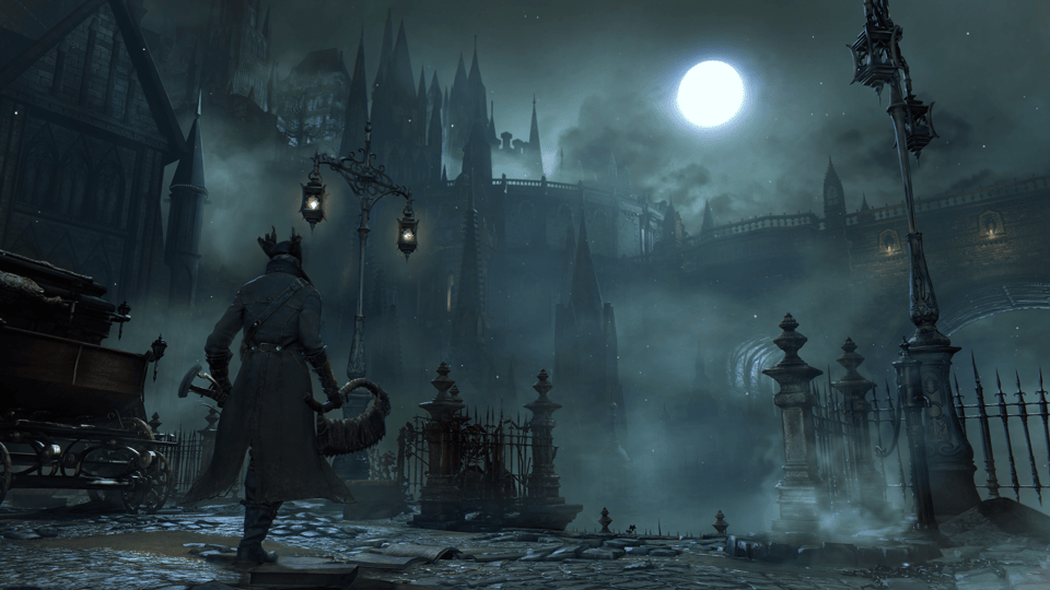 An image from Bloodborne, showing the desolate Gothic-Victorian city of Yharnam in twilight, its many citadels, bridges, and lightposts in glorious grey disarray. A lone figure in a long leather coat and hat with a vicious-looking hacksaw stands in the foreground looking into the distance.