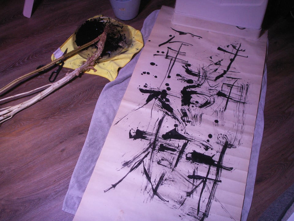 The Chinese characters "十年樹木百年樹人" drawn crudely in ink on a paper scroll.